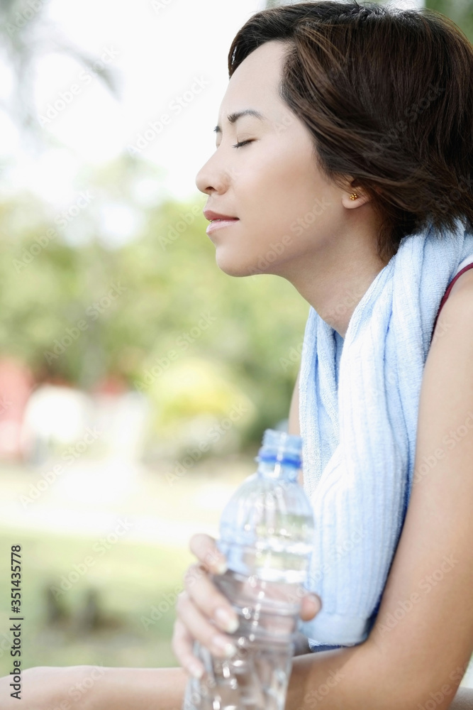 Woman with towel around the neck holding water bottle Woman with towel around the neck holding water bottle