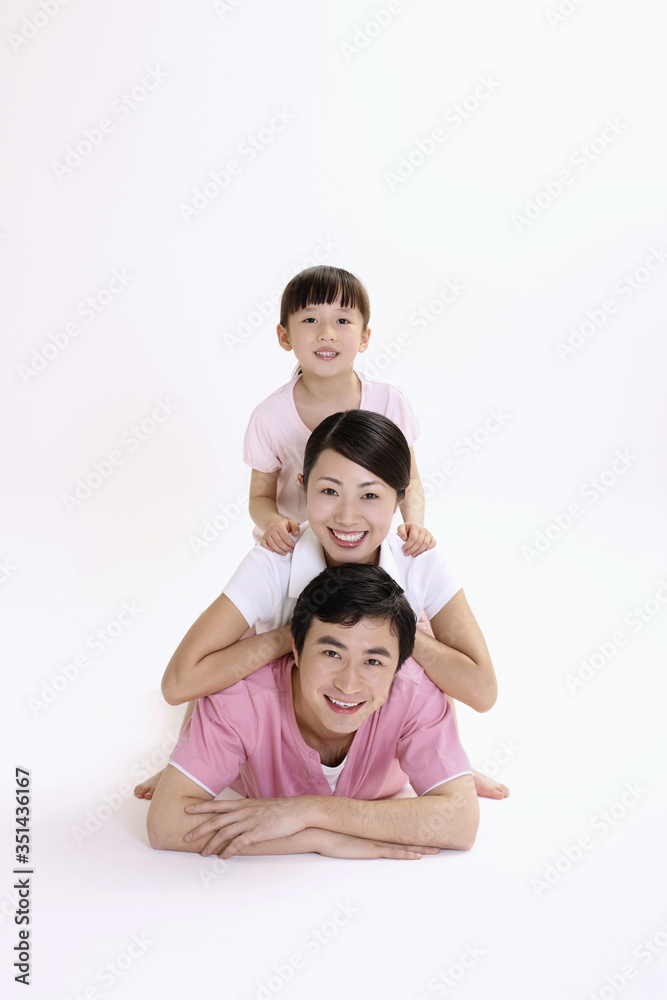 Man lying forward with woman and girl smiling behind him