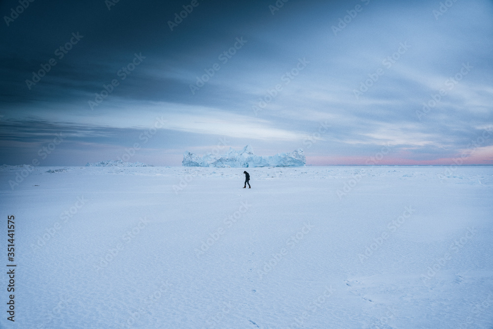 Man walking through the snow at Ilulissat, Greenland Man walking through the snow at Ilulissat, Greenland