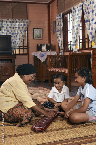 Senior woman playing congkak with her grandchildren