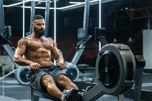 Young strong bearded bodybuilder doing low cable pulley row seated