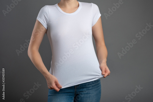 image of a young hipster girl in blank white t-shirt and blue jeans, mock up blank white t-shirt, gray background, isolate