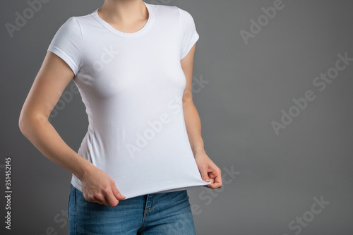 Girl in a white T-shirt with space for logos, advertising, notes. On a gray background for design and replacement background, isolate