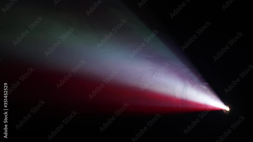 Smoke in color beam of video projector against dark background