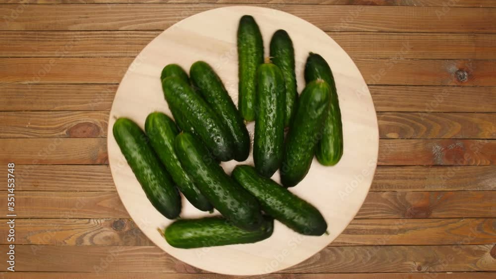 Spinning board with fresh cucumbers on wooden background, top view Spinning board with fresh cucumbers on wooden background, top view