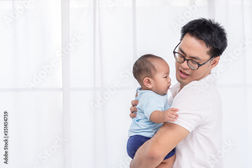 Young Asian Father spending time, take care of baby at home. Fatherhood, family concept