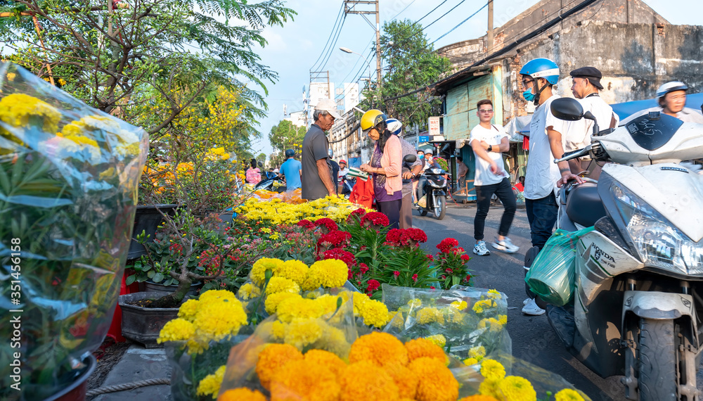 Obraz premium Bustle buying flowers at flower market along street, locals buy flowers for decoration house on Lunar New Year in Ho Chi Minh City, Vietnam.