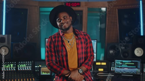 Portrait of Successful Young Black Artist, Musician, Audio Engineer, Producer Wearing Stylish Hat and Standing in Music Record Studio
