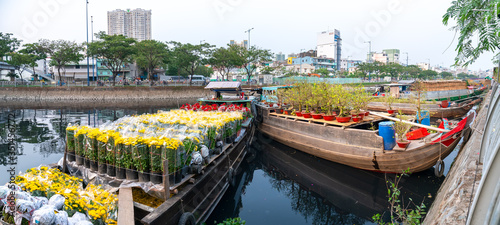 Flower boats full of flowers parked along canal wharf, a place for bustling flower market trade lunar new year in Ho Chi Minh City, Vietnam