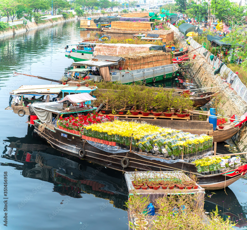 Flower boats full of flowers parked along canal wharf, a place for bustling flower market trade lunar new year in Ho Chi Minh City, Vietnam