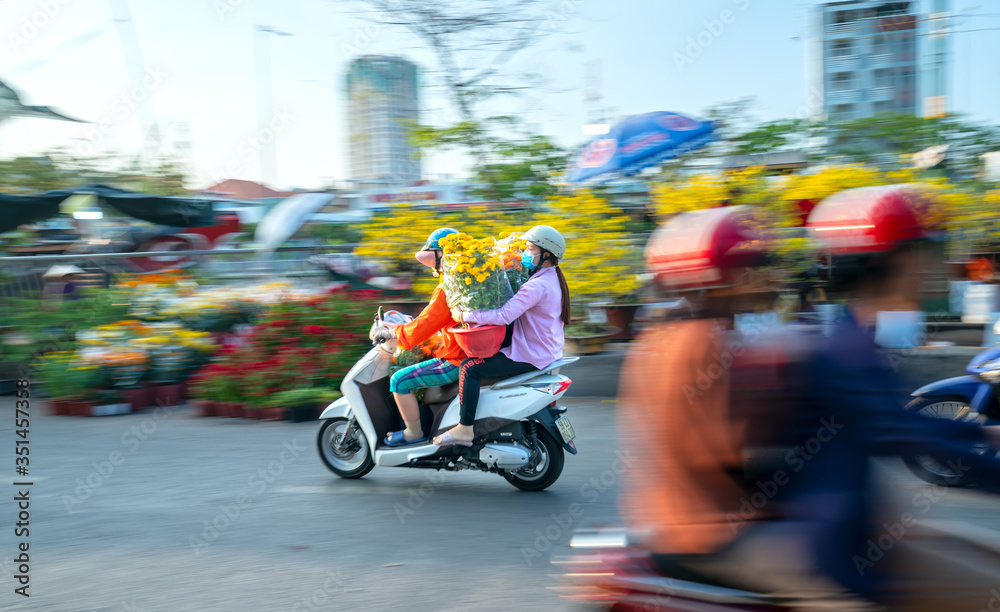 People Vietnamese driving a motorbike with holder flower pot behind, flowers buying for home decoration welcome Lunar New Year in Ho Chi Minh, Vietnam