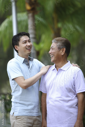 Man giving his father a pat on the shoulder while talking