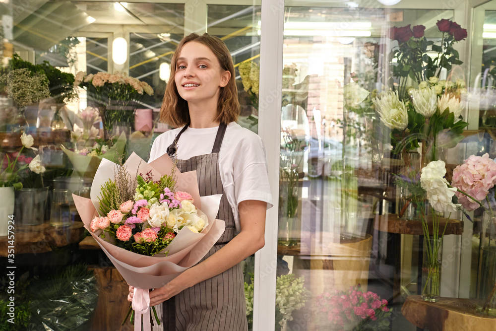 small business owner of retail flower shop and garden center holds composition of flowers. woman florist entrepreneur shopkeeper with a bouquet on background of glass showcase copy space