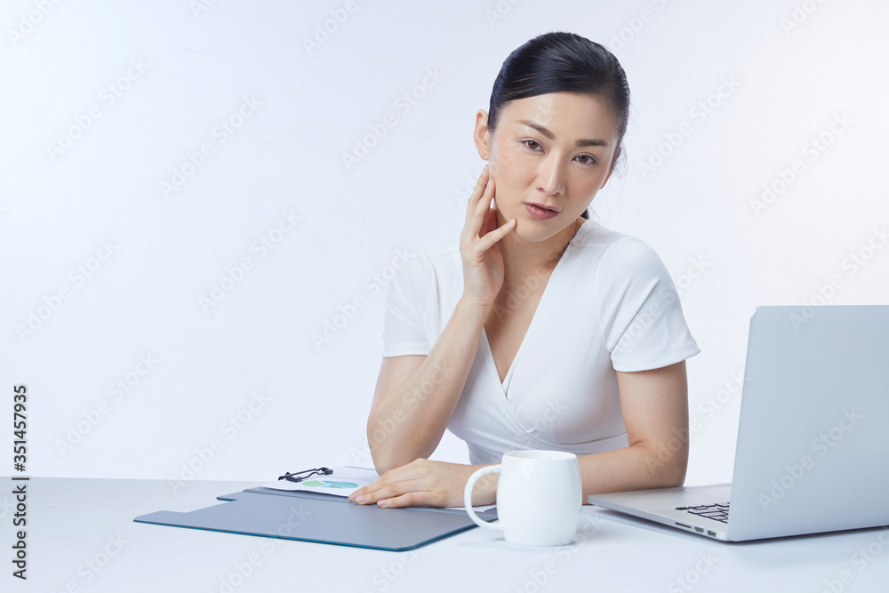 Concept businesswoman. Photo of successful asian woman sitting at table and working with documents and laptop, isolated over white background in studio. Concept businesswoman. Photo of successful asian woman sitting at table and working with documents and laptop, isolated over white background in studio.