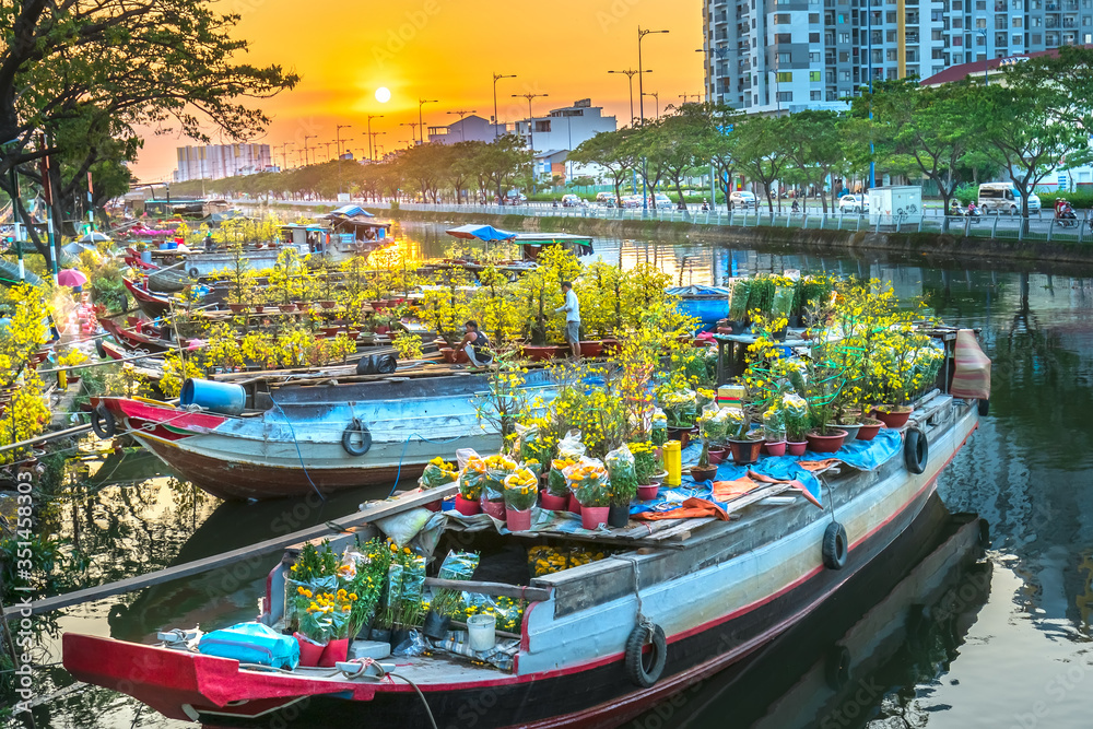 Obraz premium Flower boats full of flowers parked along canal wharf in sunset, a place for bustling flower market trade lunar new year in Ho Chi Minh City, Vietnam
