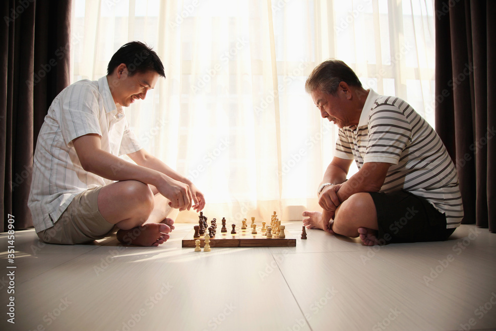 Father and son playing chess game in the room Father and son playing chess game in the room