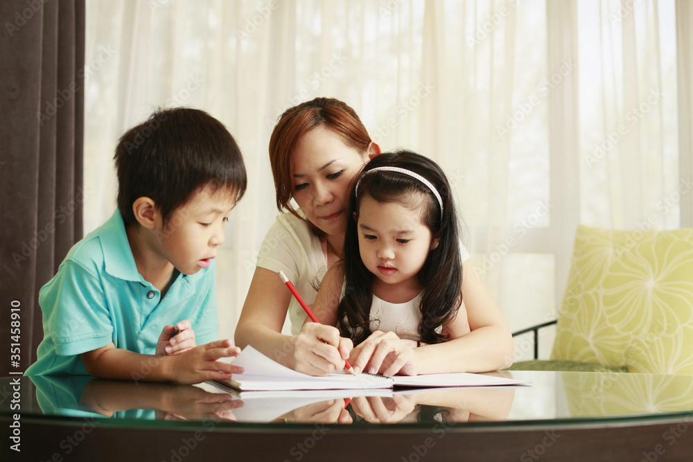 Mother watching her children doing homework Mother watching her children doing homework