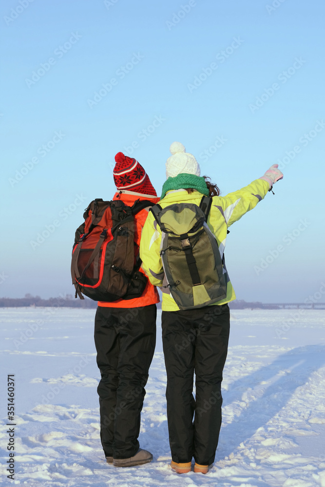 Women in warm clothing and backpacks looking for direction
