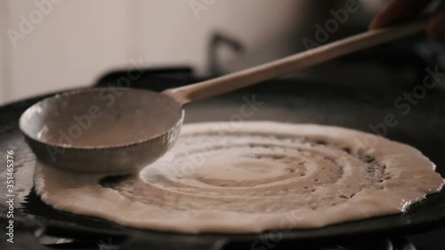 Closeup of making steaming hot 'Dosa' on a cast iron pan. Dosa is the Indian version of pancake made with rice flour dough