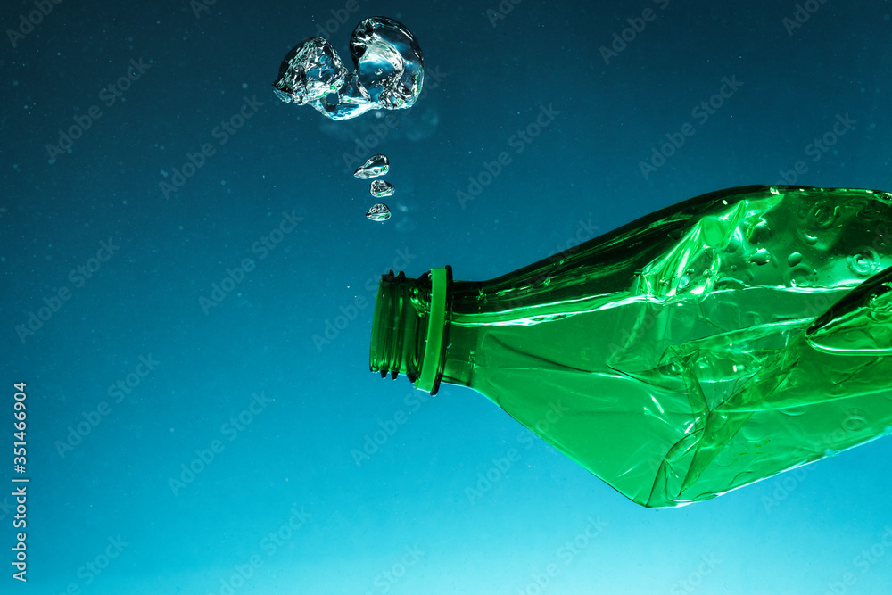 Crumpled plastic bottle polluting the ocean - obrazy, fototapety, plakaty 