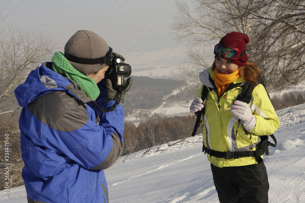 Man taking picture of woman on winter day Man taking picture of woman on winter day