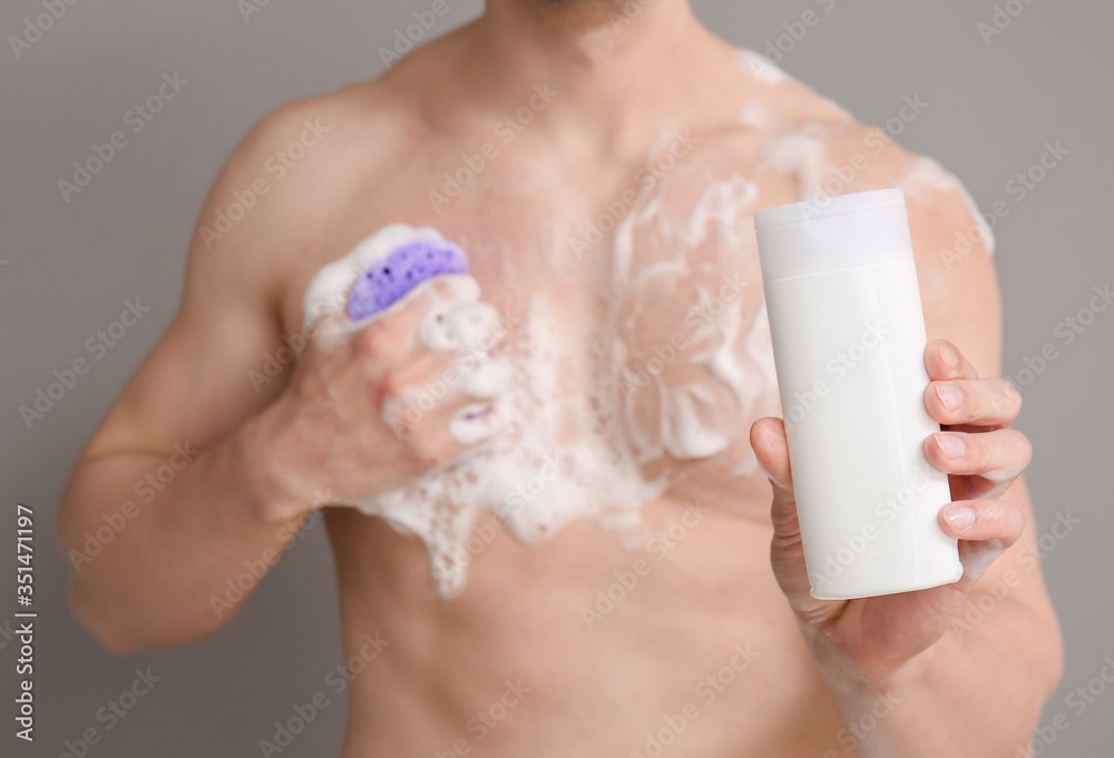 Handsome man taking shower against grey background Handsome man taking shower against grey background