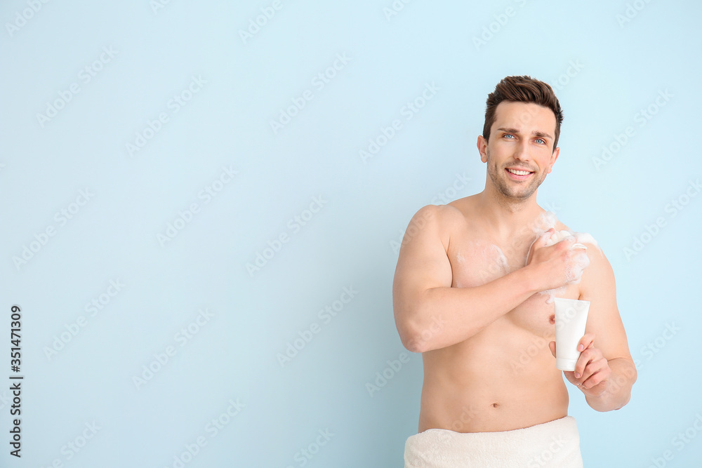 Handsome man taking shower against color background