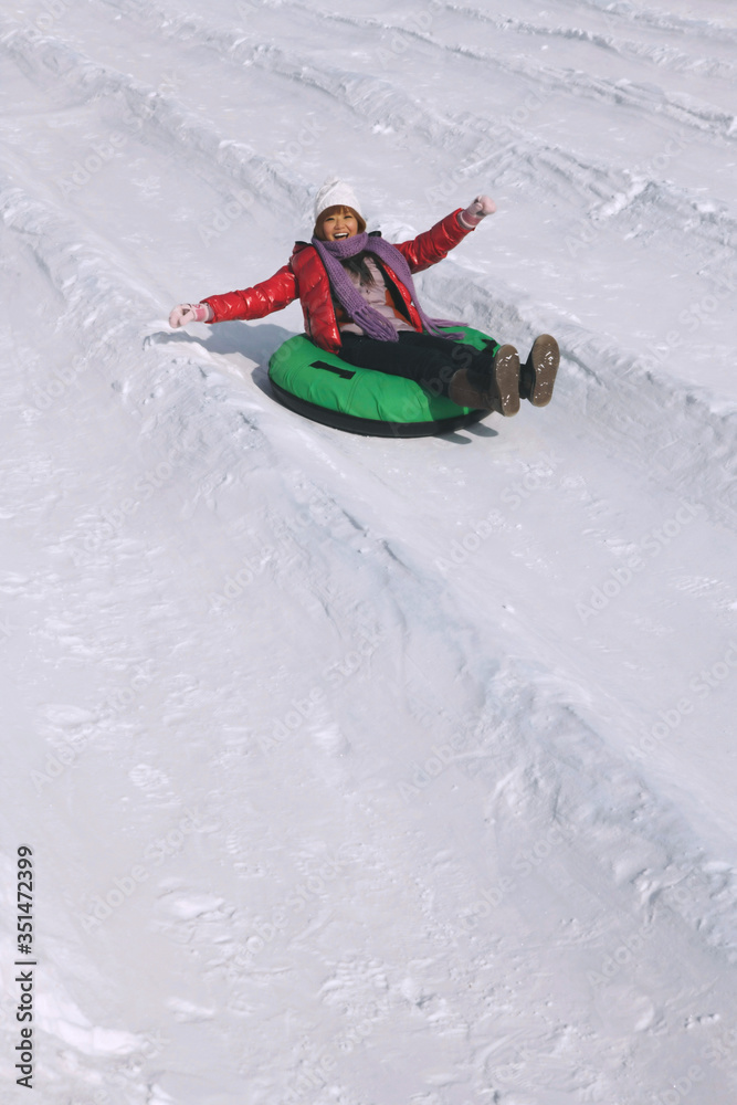 Woman sliding down snowy hill on inner tube