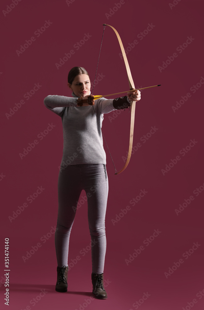 Beautiful woman with crossbow on color background Beautiful woman with crossbow on color background