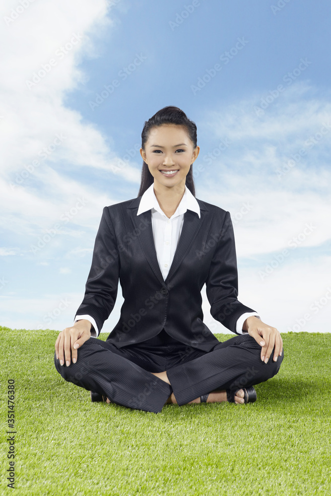 Young Asian businesswoman sitting cross-legged outdoors Young Asian businesswoman sitting cross-legged outdoors