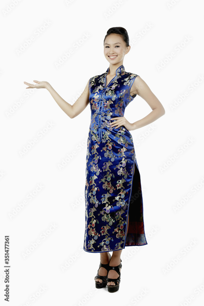 Woman in cheongsam smiling with welcoming hand gesture Woman in cheongsam smiling with welcoming hand gesture