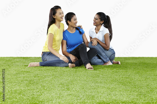 Three young women sitting on the grass, chatting