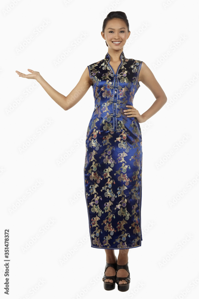Woman in cheongsam smiling with welcoming hand gesture Woman in cheongsam smiling with welcoming hand gesture