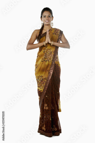Woman in sari smiling with hands clasped as a greeting