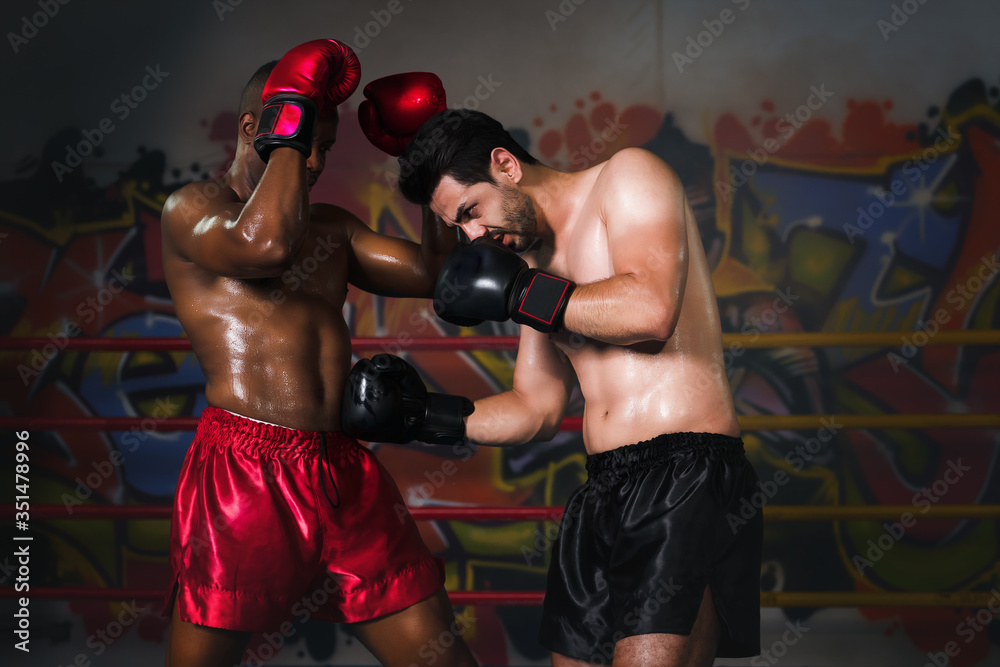 caucasian boxer making hook to african american boxer who lose guard block in boxing fight match on stage, selective focused caucasian boxer making hook to african american boxer who lose guard block in boxing fight match on stage, selective focused
