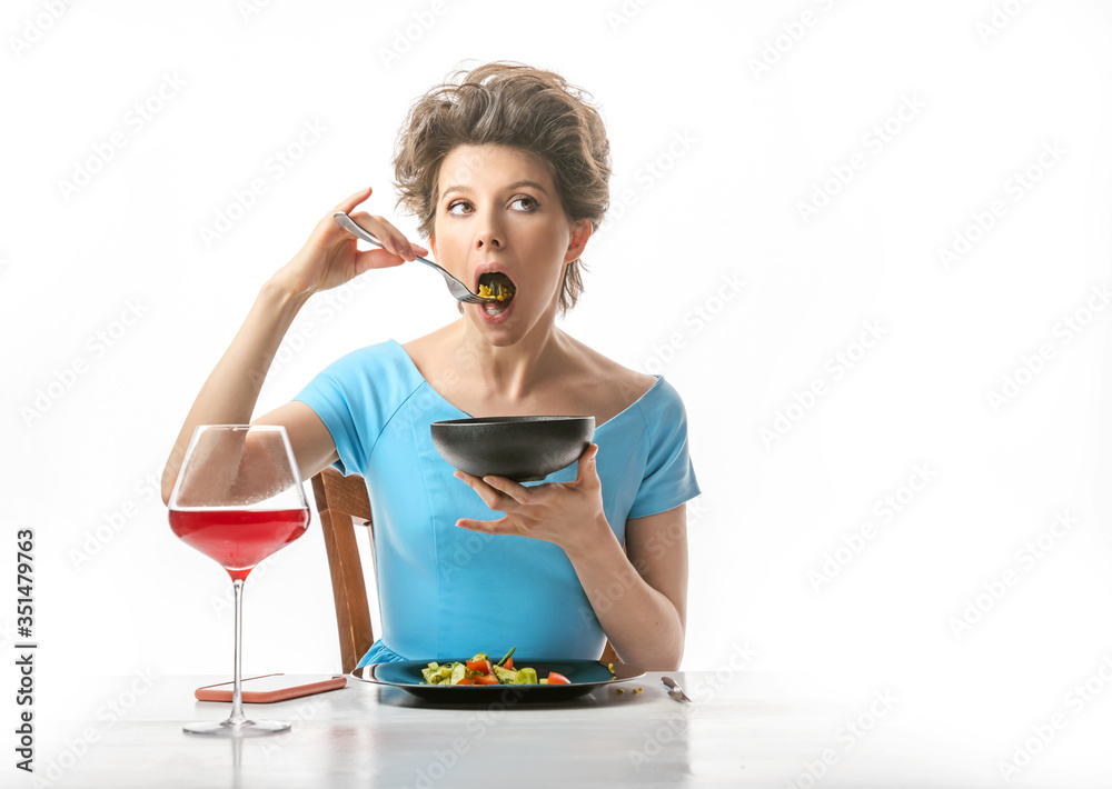 Beautiful woman eats porridge and vegetable salad. White background Beautiful woman eats porridge and vegetable salad. White background