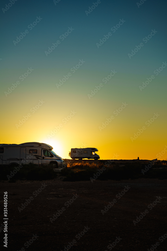 Camper cars on beach at sunset