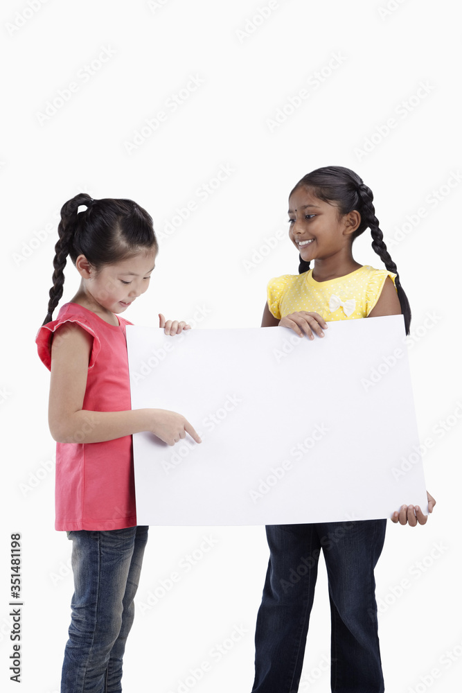 Girls holding and pointing at blank placard Girls holding and pointing at blank placard