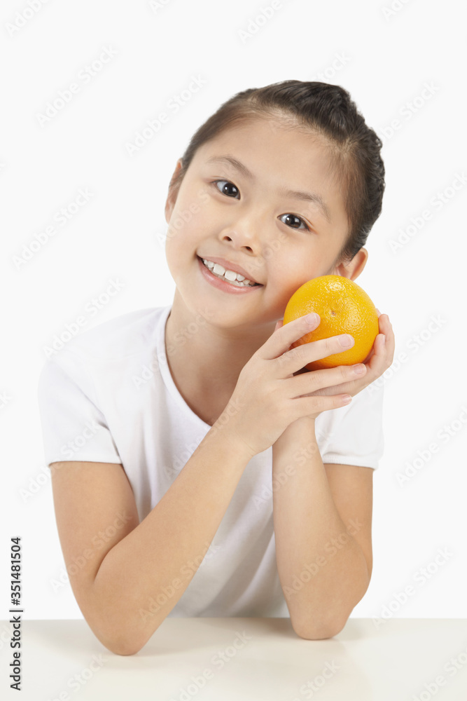 Girl smiling and holding an orange