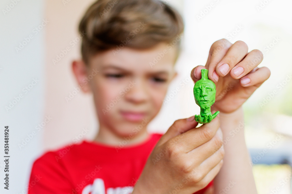 Fototapeta premium A little boy shows a craft made of plasticine