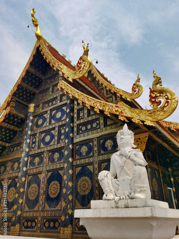 Naklejka premium Buddhist religious art, decorated and gilded facade of a temple and white statue.