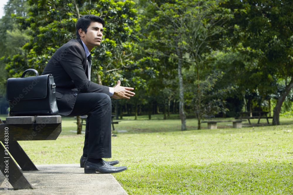 Young Asian businessman sitting on a park bench Young Asian businessman sitting on a park bench