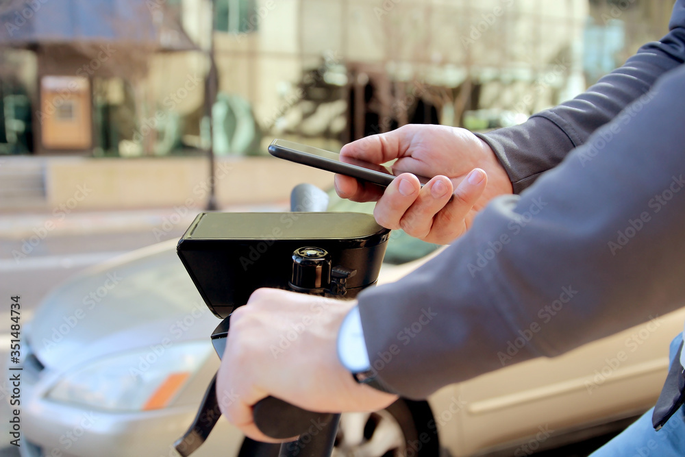 Close up image of a man on an electric scooter paying online by mobile phone Close up image of a man on an electric scooter paying online by mobile phone