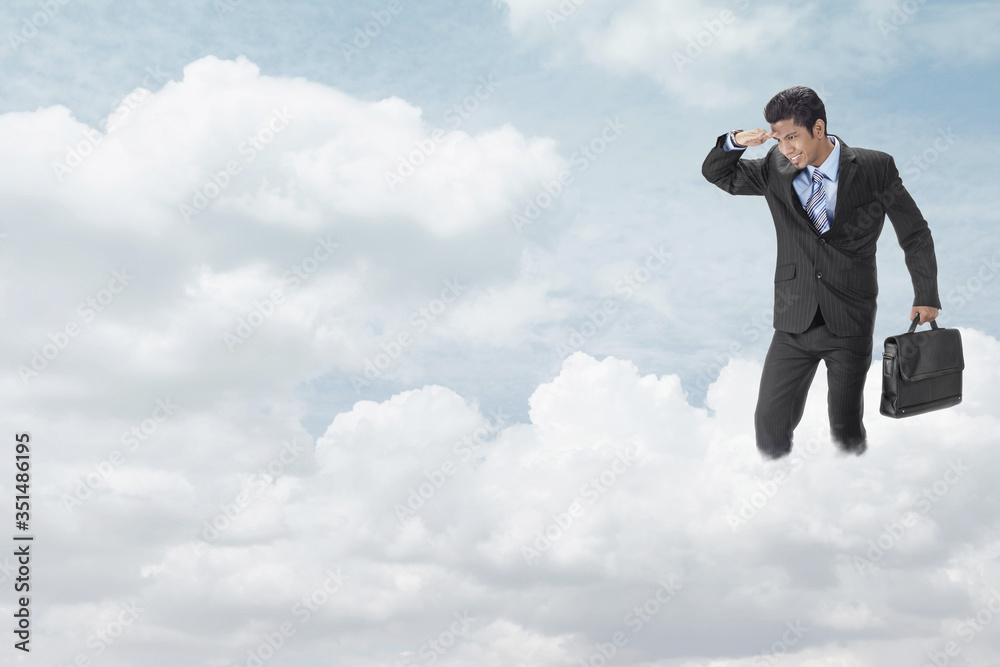 Young businessman standing on clouds, looking below Young businessman standing on clouds, looking below