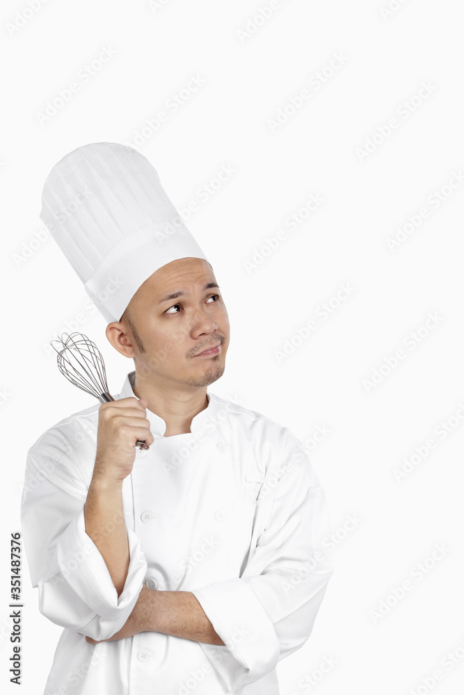 Asian chef with whisk, deep in thought Asian chef with whisk, deep in thought