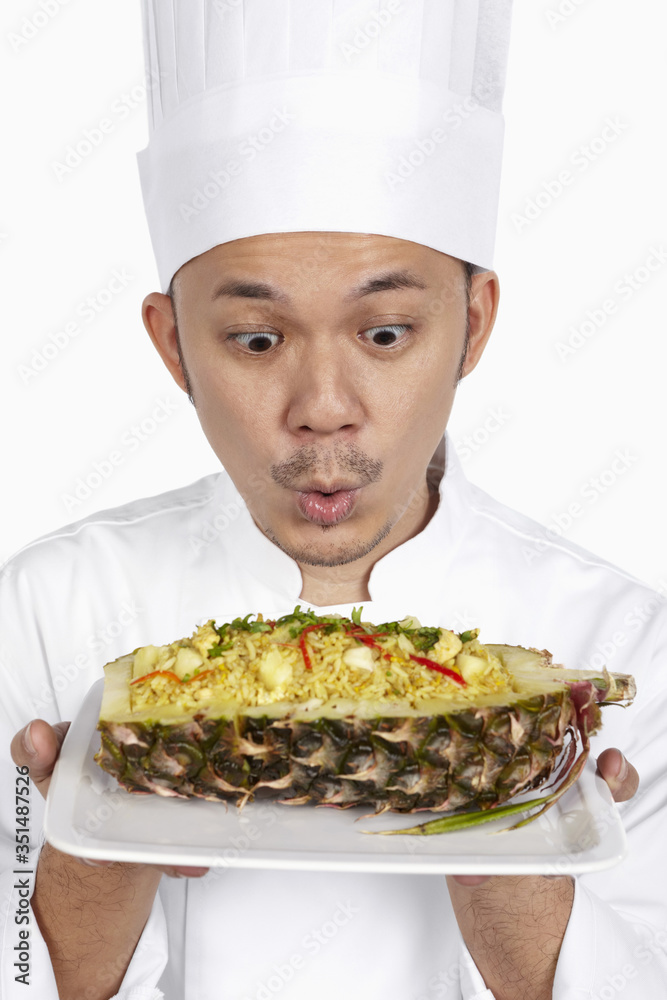 Asian chef with a plate of Thai pineapple fried rice Asian chef with a plate of Thai pineapple fried rice
