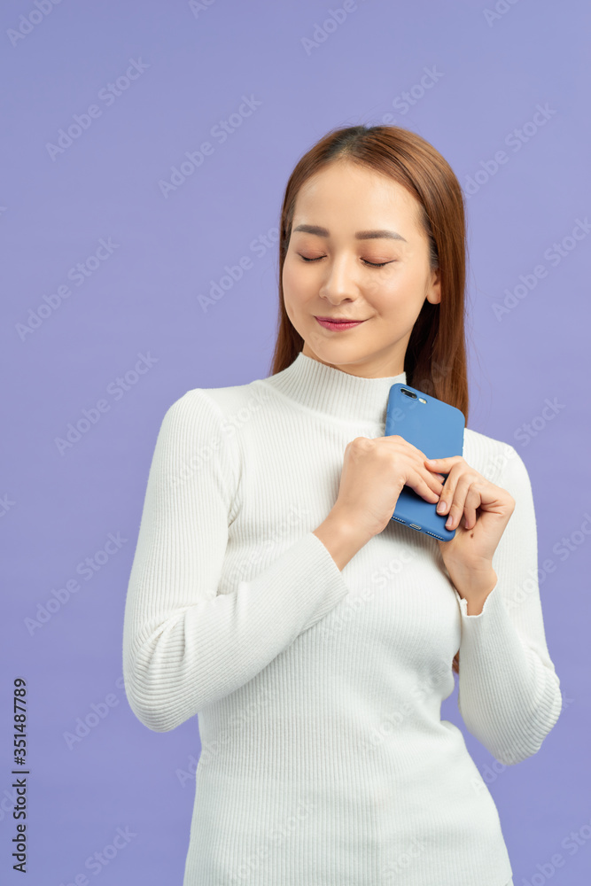 Front portrait of young smiling woman using mobile phone against violet background Front portrait of young smiling woman using mobile phone against violet background