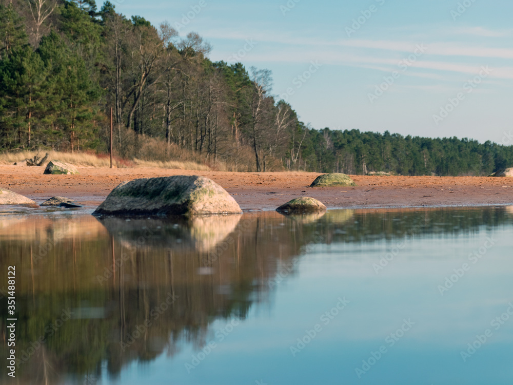 Obraz premium seascape on a sunny spring day, sandy sea shore, rocks on the shore