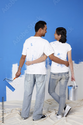 Man and woman with paint and paint roller looking at each other