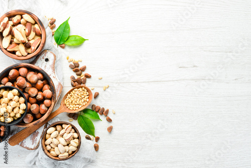 Assortment of nuts in bowls on white wooden background. free space for your text. Top view.